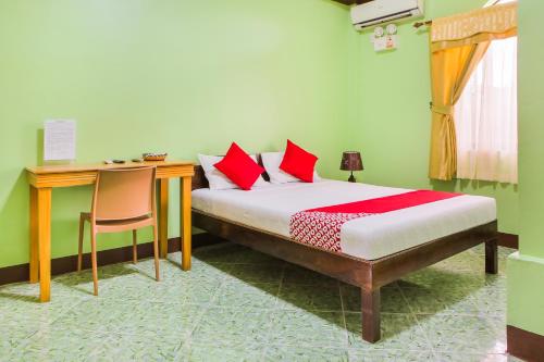 a bedroom with a bed with red pillows and a desk at OYO 422 Villa Emilia Pension House in Panglao