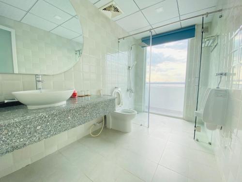 a white bathroom with a sink and a toilet at Hung Phuoc Hotel in Bến Cát