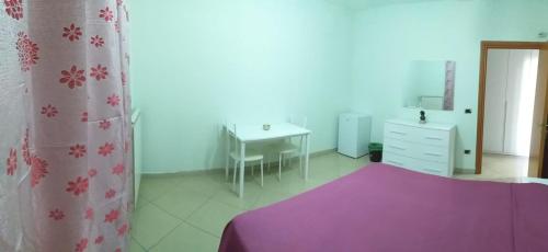 a bedroom with a purple bed and a desk and a table at Green House in Nola