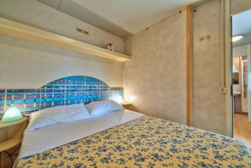 Camping Village Mareblu في مارينا دي سيسينا: غرفة نوم مع سرير مع اللوح الأمامي الأزرق