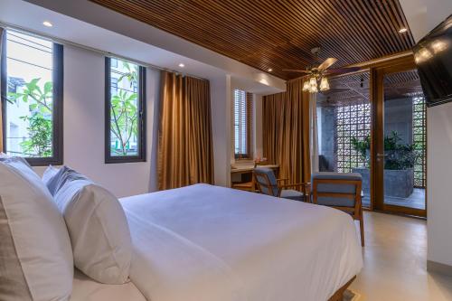 een slaapkamer met een groot wit bed en een bureau bij Daisy Boutique Hotel in Da Nang