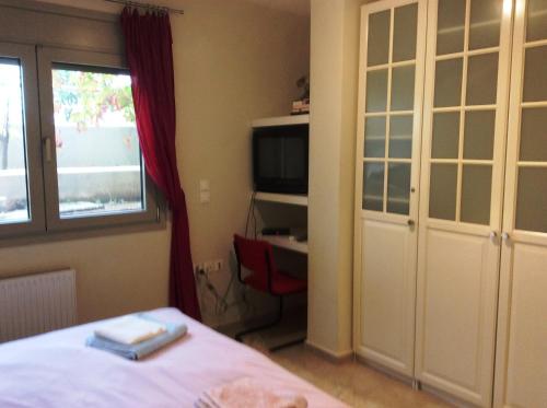 a bedroom with a bed and a window and a television at Sunset at Cape Sounio in Sounio