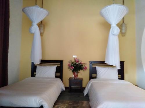 two beds in a room with flowers on the wall at Mai Chau Rustic Home in Mai Chau