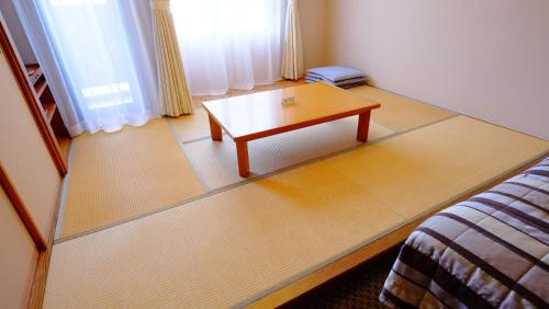 a room with a coffee table and a bed at Hotel Harvest Skijam Katsuyama in Katsuyama