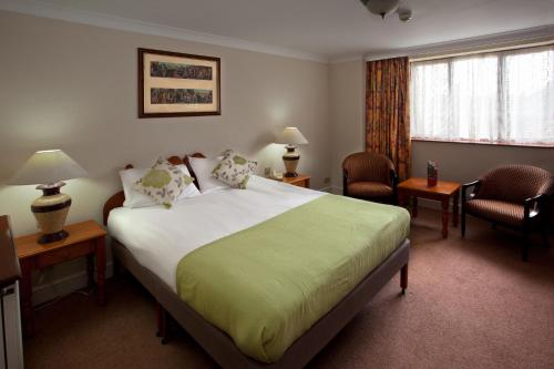 a hotel room with a large bed and two chairs at Royal Court Hotel & Spa Coventry in Coventry