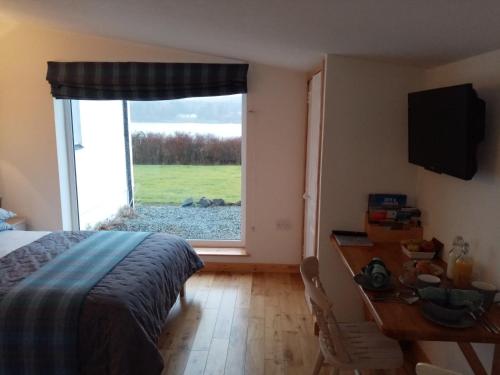 Kiloran Self Catering Suite في Skeabost: غرفة نوم بسرير ومكتب ونافذة