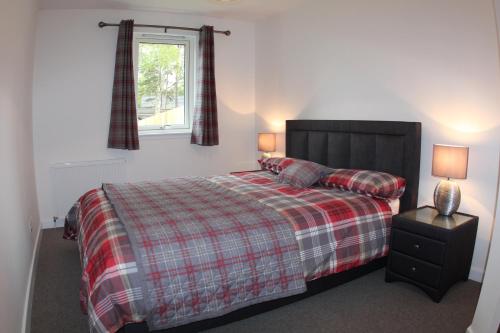 sypialnia z łóżkiem z kocem i oknem w obiekcie 2 Dellmhor Cottages w Aviemore
