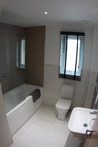 a bathroom with a tub and a toilet and a sink at 2 Dellmhor Cottages in Aviemore