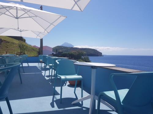 a row of tables and chairs with a view of the ocean at Lofts Azul Pastel in Horta