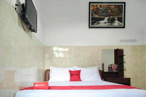 um quarto com uma almofada vermelha numa cama em RedDoorz @ Hotel Surabaya Sumenep em Sumenep