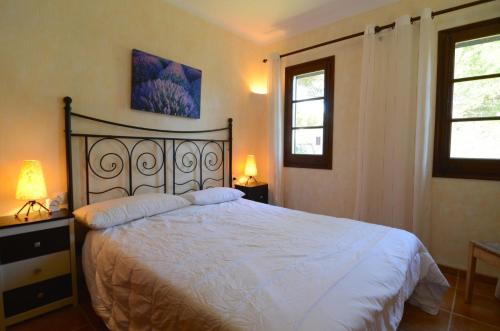 ein Schlafzimmer mit einem Bett mit weißen Laken und zwei Fenstern in der Unterkunft PIVERD DEL GOLF 58 in Pals