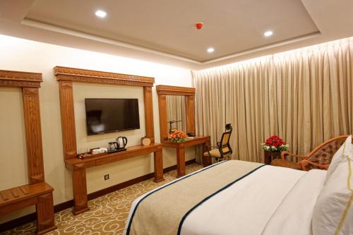 a hotel room with a bed and a television at Royal Swiss Lahore in Lahore
