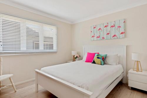 a white bedroom with a white bed and a window at Ocean Breeze in Huskisson