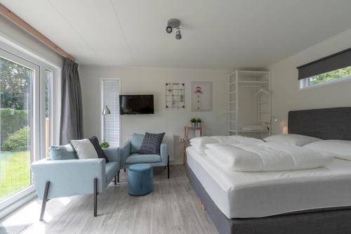 a bedroom with a large white bed and a chair at Chalet studio Mees - Texel in De Koog
