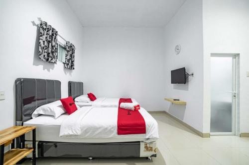 a white bedroom with a bed with red pillows at RedDoorz Plus near Thamrin Plaza Medan in Medan