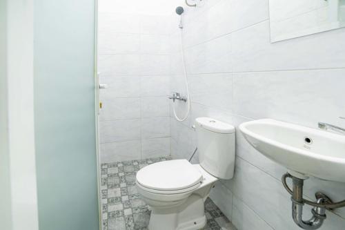 a white bathroom with a toilet and a sink at RedDoorz Plus near Thamrin Plaza Medan in Medan