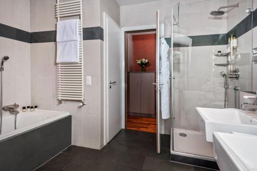 a bathroom with a tub and a sink and a shower at Hôtel Résidence Parc des Eaux Vives in Geneva