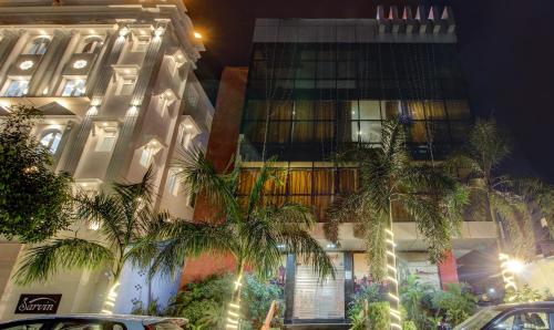 a tall building with palm trees in front of it at Hotel Amanda in Lucknow