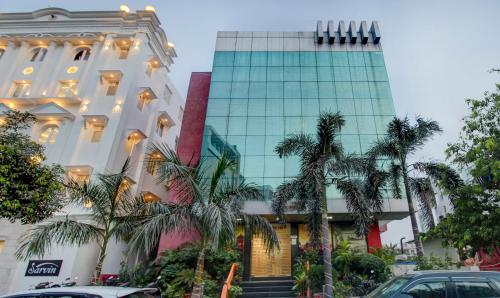 a tall building with palm trees in front of it at Hotel Amanda in Lucknow