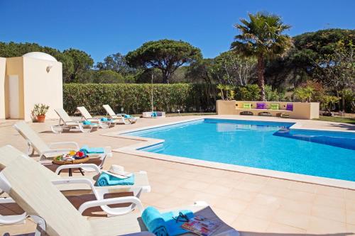 a pool with chaise lounge chairs and a swimming pool at Villa Tulum by Algarve Vacation in Almancil