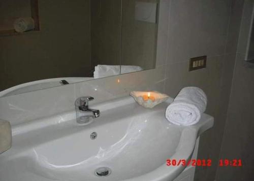 un bagno bianco con lavabo, specchio e asciugamani di BB La casa di Tella a Carosino