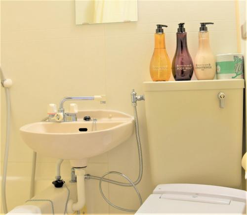 a bathroom with a sink and bottles on a shelf at Osaka U-Shuku in Osaka