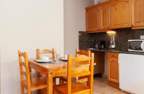 una cucina con tavolo in legno, sedie e bancone di Wuau! Apartamentos Solana de Ransol a Ransol