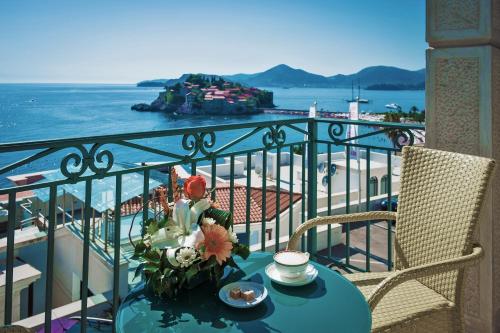 a table with a vase of flowers on a balcony at Boutique Hotel Azimut in Sveti Stefan