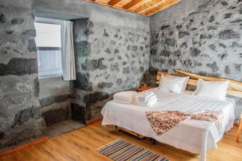 a bedroom with a bed with a stone wall at Aldeia da Gingeira in São Mateus