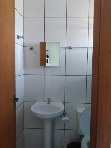 a white bathroom with a sink and a toilet at Pousada Recanto da Barra Imbé in Imbé