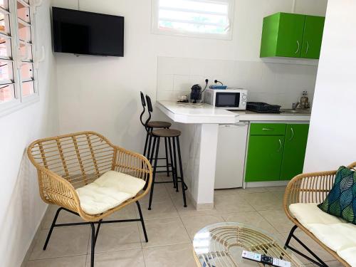 une cuisine avec des armoires vertes, une table et des chaises dans l'établissement Le ZANDOLI (Appartement avec vue), à Petit-Bourg