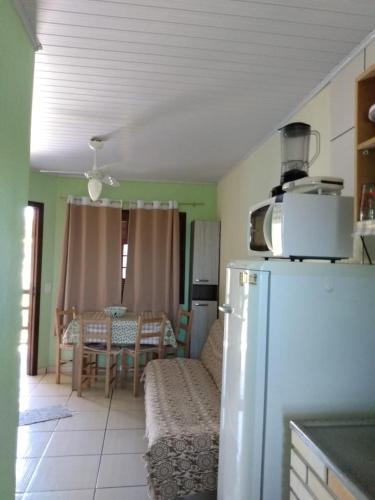 a kitchen with a refrigerator and a dining room with a table at Pousada Recanto da Barra Imbé in Imbé