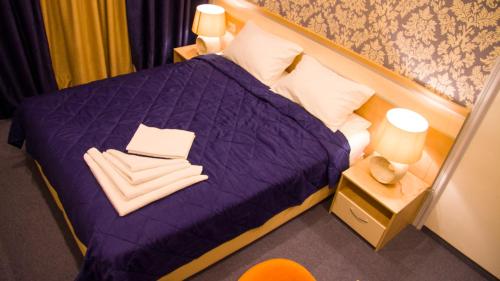 a bedroom with a purple bed with towels on it at Гостиница ОТЕЛИКА in Syktyvkar