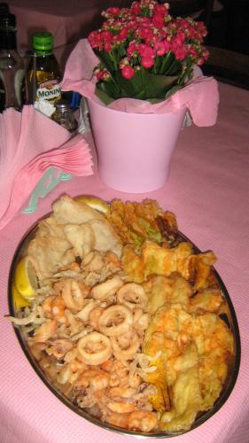 a plate of food on a table with a pot of flowers at Hotel Serafini Misano Adriatico in Misano Adriatico