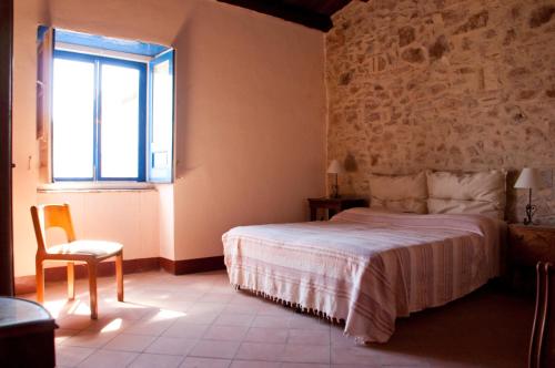 a bedroom with a bed and a window and a chair at Fontanarossa in Cerda