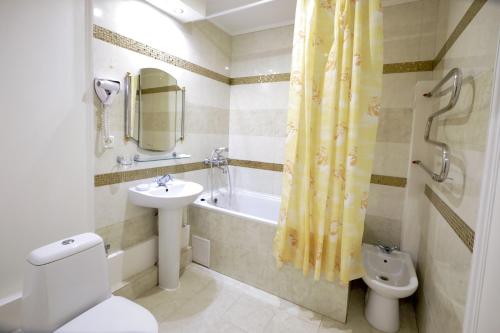 a bathroom with a sink and a toilet and a bath tub at VICTOR Hotel Resort & SPA in Truskavets