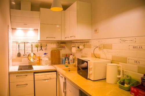a kitchen with white cabinets and a white microwave at Гостиница ОТЕЛИКА in Syktyvkar