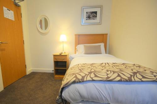 a bedroom with a bed and a lamp on a night stand at The Burlington Hotel in Cleethorpes