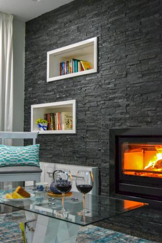 a living room with a fireplace and two glasses of wine at Casinha do Eido Novo - Alojamento Local in Valença