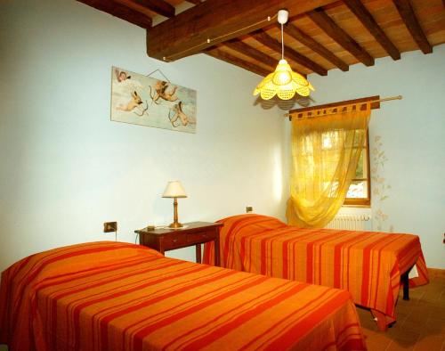 a bedroom with two beds with orange striped sheets at Borgo del Sole Agriturismo in Poggio