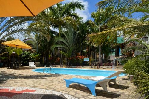 uma piscina com duas cadeiras e um guarda-sol em Pousada Chácara Porto do Sol em Jacumã
