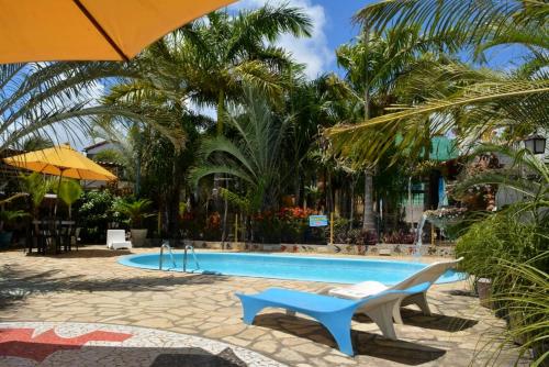 a swimming pool with two chairs and an umbrella at Pousada Chácara Porto do Sol in Jacumã