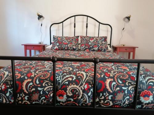 a bed with a black and red bedspread and two tables at Casa Vista Bella in El Cercado