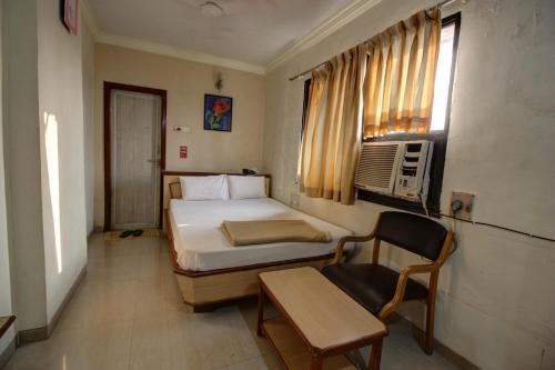 a bedroom with a bed and a chair and a window at Hotel Jay International in Vapi