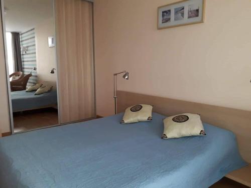 a bedroom with a blue bed with a large mirror at Elijos apartamentai in Šventoji