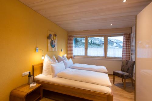 - une chambre avec un lit doté de draps blancs et une fenêtre dans l'établissement Appartement Seebachsee, à Warth am Arlberg