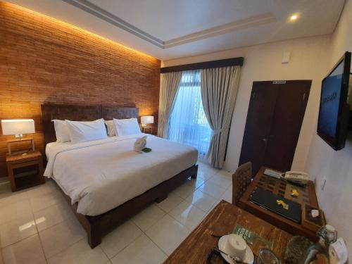 a bedroom with a bed and a table and a television at Hotel Genggong in Candidasa
