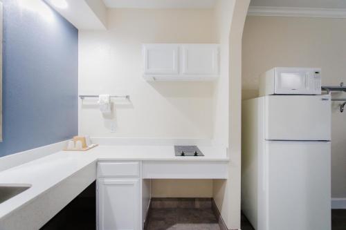 eine weiße Küche mit einer Spüle und einem Kühlschrank in der Unterkunft Palace Inn TX-249 in Houston