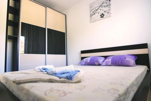 a bedroom with a bed with purple pillows and a mirror at Apartments Villa Zora in Star Dojran