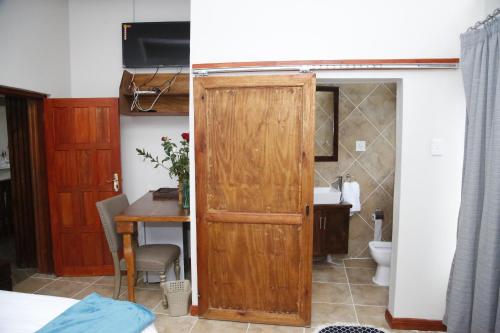 a bathroom with a wooden door next to a table at Travetel OR Tambo Airport in Kempton Park